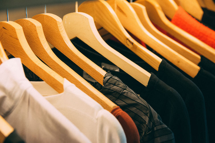 Vêtements sur des cintres afin d’illustrer l’article sur les magasins de vêtements d’occasion qui rachètent vos vêtements.