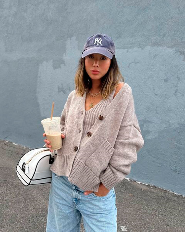 Aimee Song dans une rue avec une casquette, un sac et un verre à la main. Aimee Song, architecte, fait partie des influenceurs les plus suivis dans le monde.