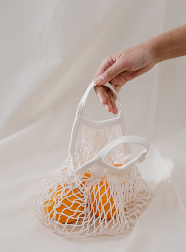sac en filet beige avec des oranges devant un fond beige afin d’illustrer l’article sur les marques de vêtements responsables