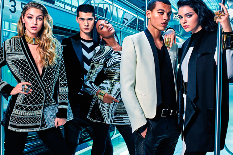 Image promotionnelle de la marque de mode de luxe, Balmain x H&M présentant des modèles comme Gigi Hadid et Kendall Jenner dans un métro avec les vêtements de la collaboration.