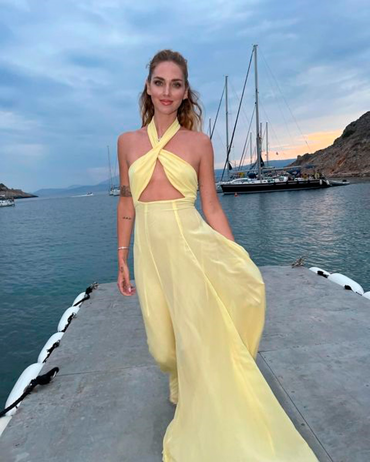 Chiara Ferragni dans une longue robe jaune posant en face d’un port. Chiara Ferragni fait partie l’une des influenceuse mode Instagram les plus connus.